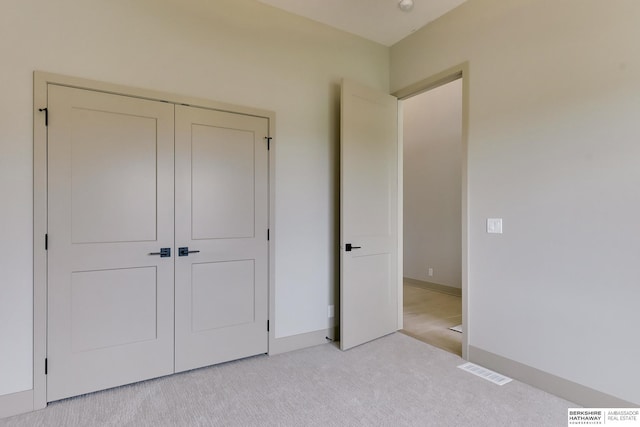 unfurnished bedroom featuring light colored carpet, baseboards, and a closet