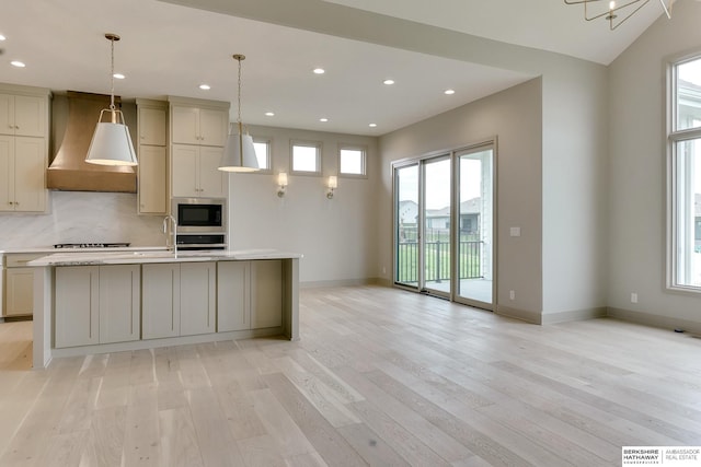 kitchen featuring wall chimney exhaust hood, built in microwave, light wood-style floors, light countertops, and baseboards