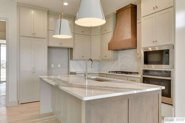 kitchen with stainless steel appliances, custom range hood, a sink, backsplash, and light stone countertops