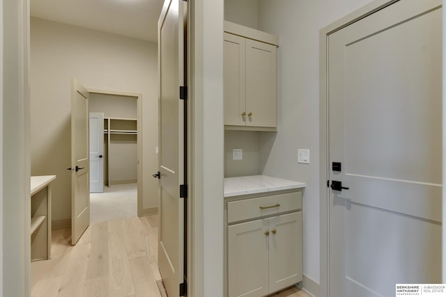 laundry room featuring light wood-style flooring and baseboards