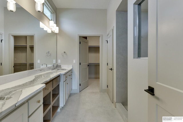 full bathroom featuring vanity, a spacious closet, and tiled shower