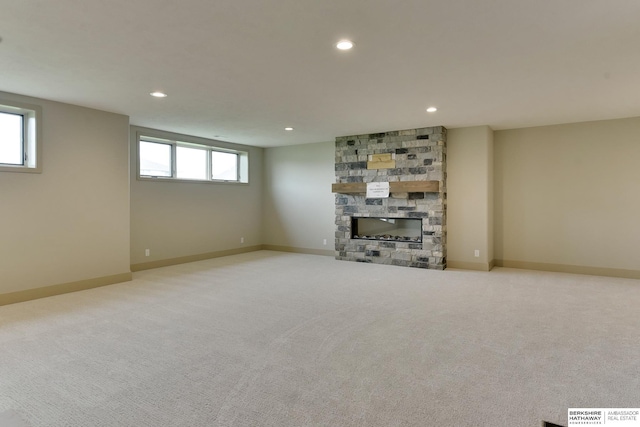 basement featuring a stone fireplace, carpet, recessed lighting, and baseboards