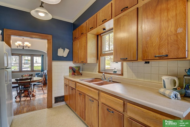 4939 Hickory St, Omaha, NE 68106 - kitchen featuring freestanding refrigerator, ornamental molding, a sink, light countertops, and a chandelier