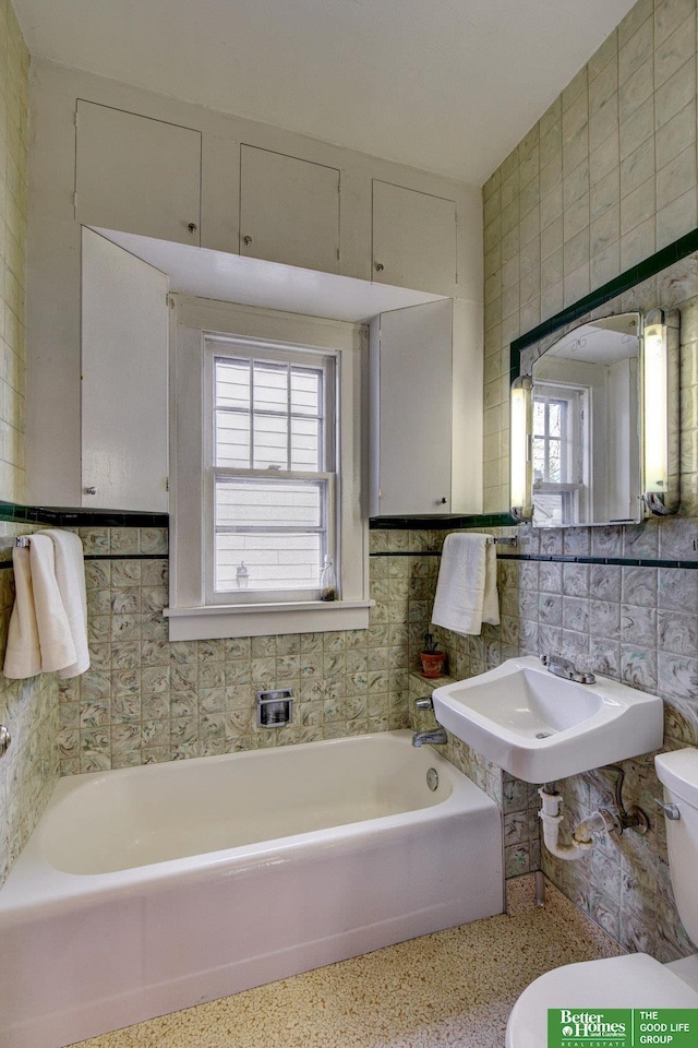 4939 Hickory St, Omaha, NE 68106 - full bathroom featuring plenty of natural light, tile walls, toilet, a bath, and speckled floor