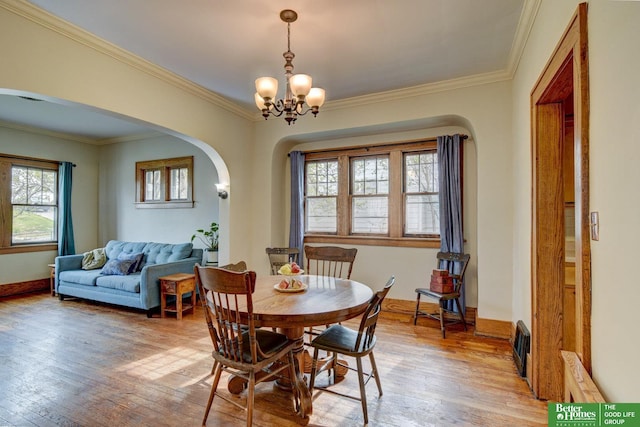 4939 Hickory St, Omaha, NE 68106 - dining space featuring arched walkways, light wood-type flooring, a chandelier, crown molding, and baseboards