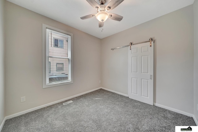 927 Garfield St, Lincoln, NE 68502 - carpeted spare room featuring baseboards, a barn door, and ceiling fan