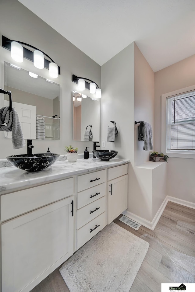 927 Garfield St, Lincoln, NE 68502 - bathroom with walk in shower, double vanity, wood finished floors, and baseboards