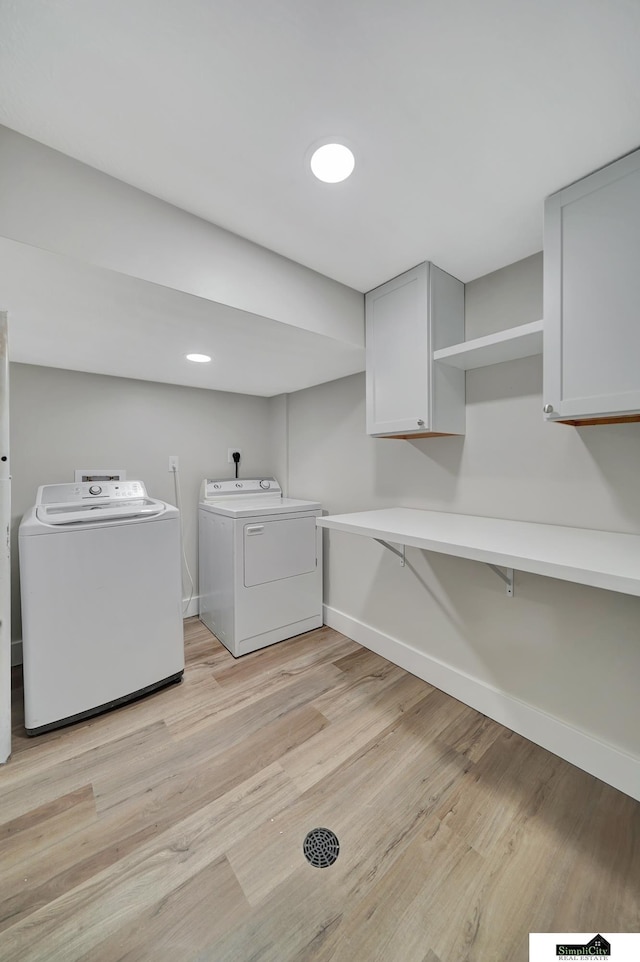 927 Garfield St, Lincoln, NE 68502 - washroom featuring washing machine and dryer, cabinet space, light wood-style floors, and baseboards