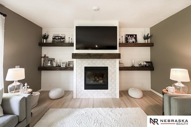 living area featuring wood finished floors, baseboards, and a fireplace
