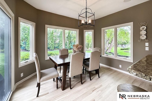 dining space with light wood-type flooring, a chandelier, plenty of natural light, and baseboards