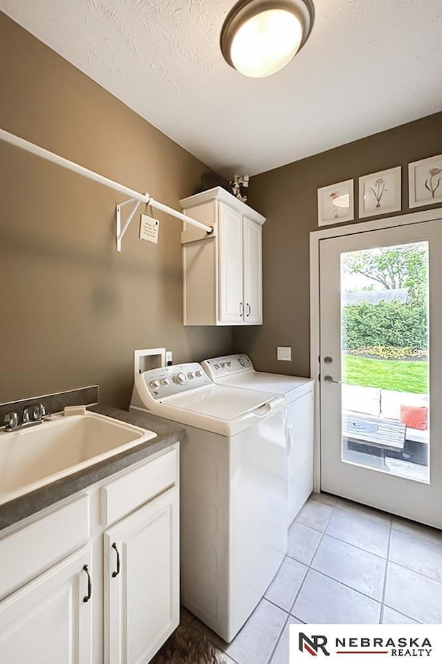 laundry room featuring separate washer and dryer, cabinet space, a textured ceiling, and light tile patterned floors