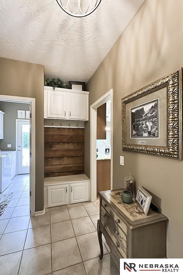 mudroom featuring washer and clothes dryer, a textured ceiling, and light tile patterned floors