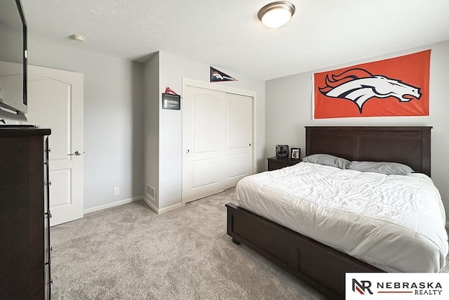 bedroom featuring light colored carpet, a closet, and baseboards