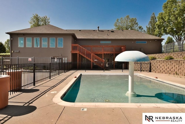 view of swimming pool with fence, stairs, and a wooden deck