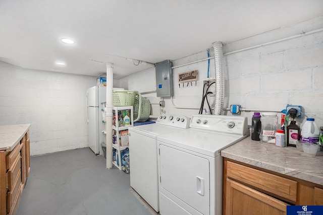 washroom with separate washer and dryer, electric panel, cabinet space, and concrete block wall