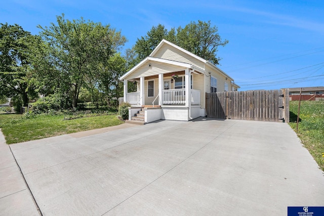 shotgun-style home featuring covered porch and a gate