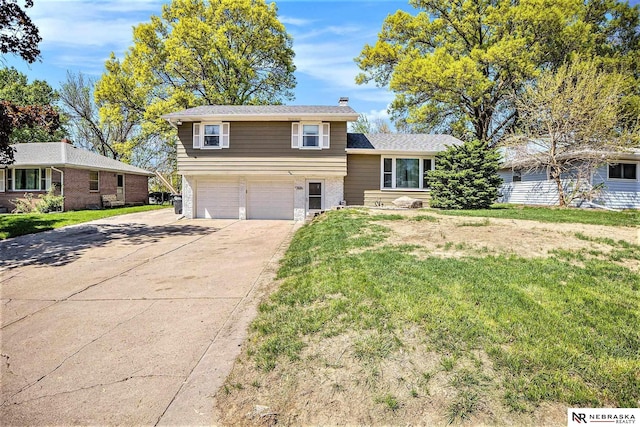 split level home featuring a garage, a front yard, driveway, and brick siding
