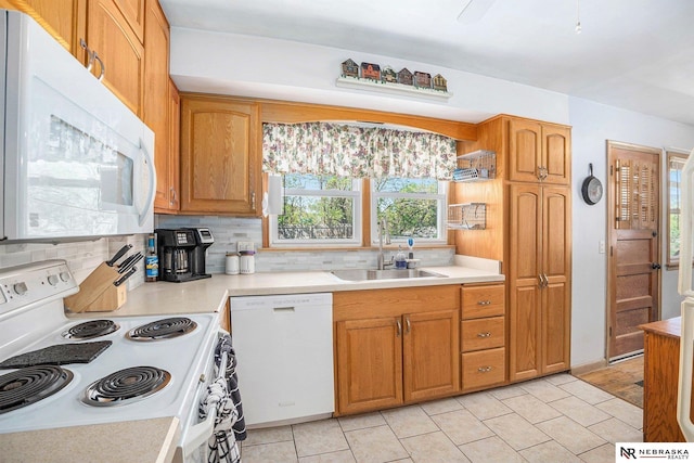 kitchen with white appliances, a sink, backsplash, and light countertops