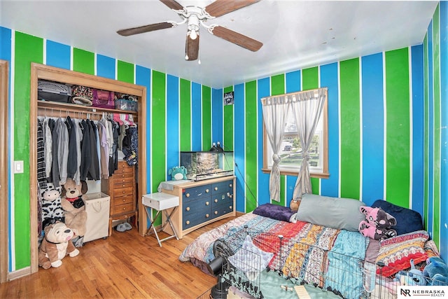 bedroom with wallpapered walls, wood finished floors, a closet, and ceiling fan