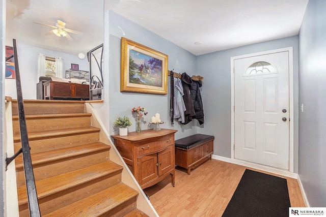 entrance foyer featuring light wood-style floors, ceiling fan, stairs, and baseboards