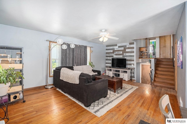 living area with hardwood / wood-style flooring, a ceiling fan, stairway, and baseboards