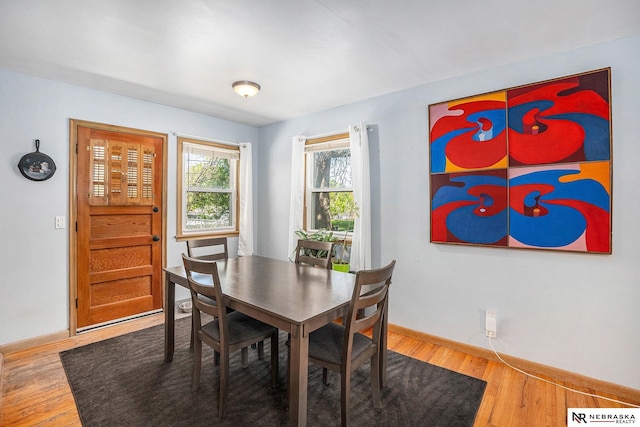 dining space with baseboards and wood finished floors