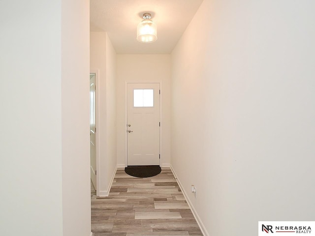 doorway with light wood-style floors and baseboards