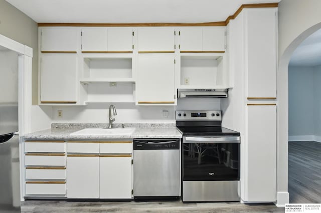 kitchen featuring stainless steel appliances, open shelves, a sink, arched walkways, and under cabinet range hood