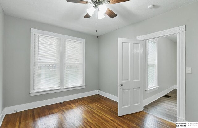 unfurnished room featuring dark wood finished floors, ceiling fan, and baseboards