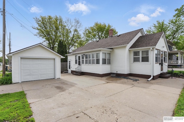 view of front of home with driveway, an outdoor structure, a shingled roof, entry steps, and a detached garage