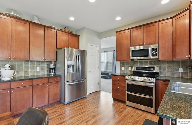 2421 Sand Hills Dr, Papillion, NE 68046 - kitchen featuring stainless steel appliances, light wood-type flooring, tasteful backsplash, brown cabinetry, and recessed lighting