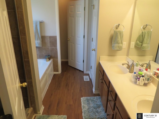 2421 Sand Hills Dr, Papillion, NE 68046 - bathroom featuring double vanity, a garden tub, wood finished floors, and baseboards