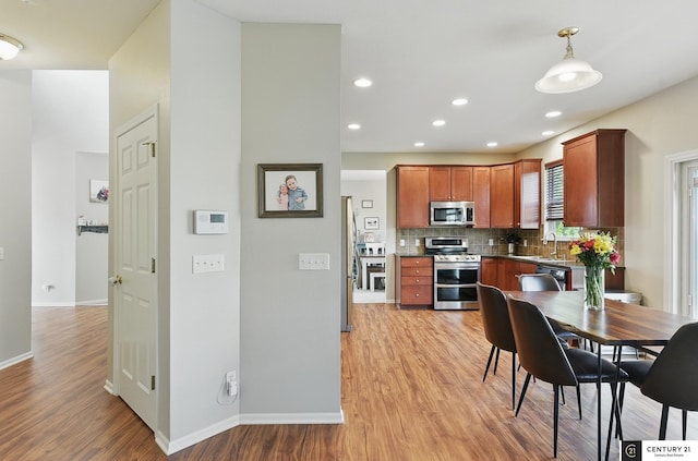 2421 Sand Hills Dr, Papillion, NE 68046 - kitchen featuring appliances with stainless steel finishes, a sink, light wood-style floors, tasteful backsplash, and dark countertops