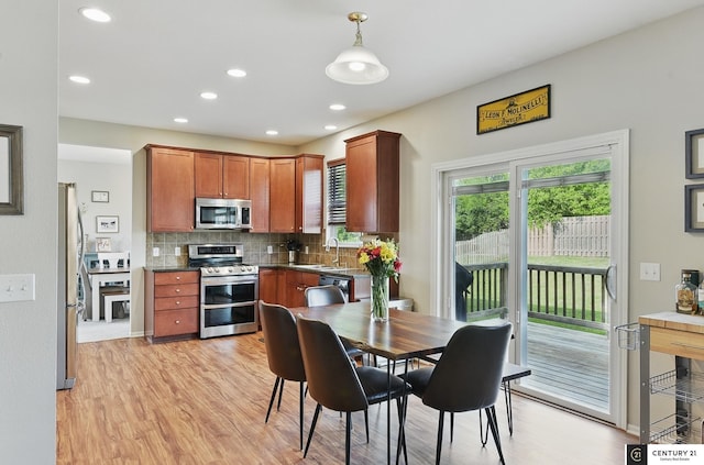 2421 Sand Hills Dr, Papillion, NE 68046 - kitchen featuring appliances with stainless steel finishes, a sink, light wood-style flooring, decorative backsplash, and dark countertops