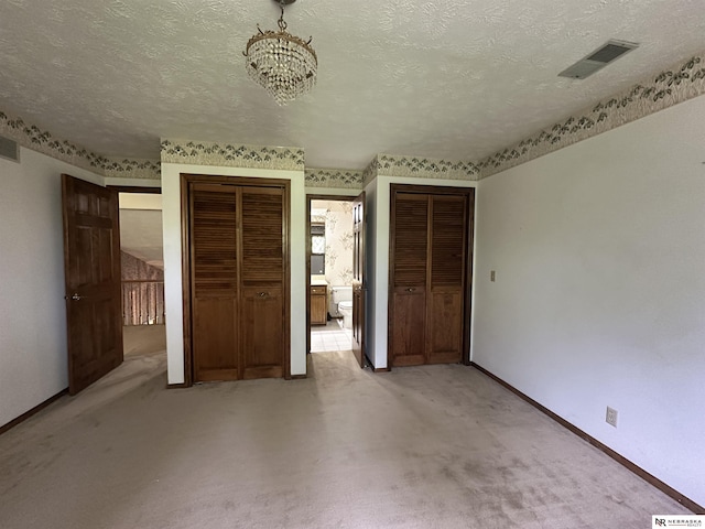 1605 S 113th Plz, Omaha, NE 68144 - unfurnished bedroom featuring two closets, a textured ceiling, baseboards, a chandelier, and light colored carpet
