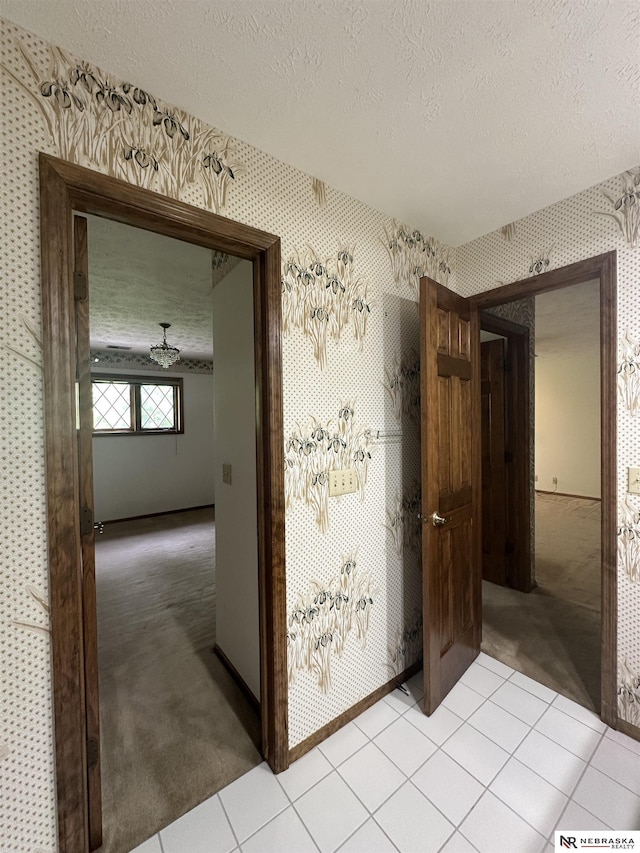 1605 S 113th Plz, Omaha, NE 68144 - hall with wallpapered walls, a textured ceiling, light colored carpet, light tile patterned flooring, and baseboards