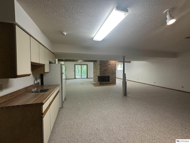 1605 S 113th Plz, Omaha, NE 68144 - basement with a sink, a textured ceiling, light carpet, a fireplace, and freestanding refrigerator