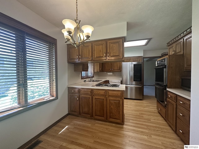 1605 S 113th Plz, Omaha, NE 68144 - kitchen featuring appliances with stainless steel finishes, a peninsula, light countertops, a chandelier, and light wood finished floors