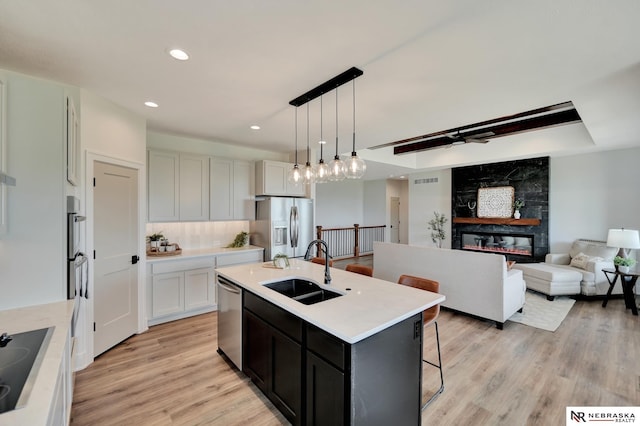 612 N 107th St, Lincoln, NE 68527 - kitchen with appliances with stainless steel finishes, a sink, light countertops, light wood-style flooring, and a center island with sink