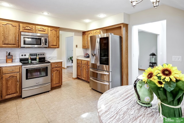 kitchen featuring appliances with stainless steel finishes, light countertops, brown cabinetry, and recessed lighting