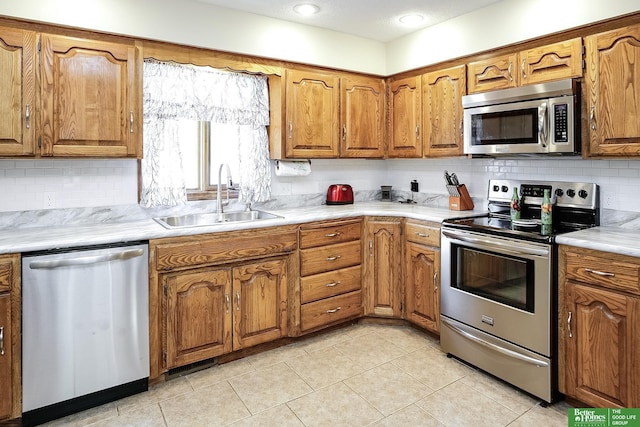 kitchen with appliances with stainless steel finishes, a sink, brown cabinets, and backsplash