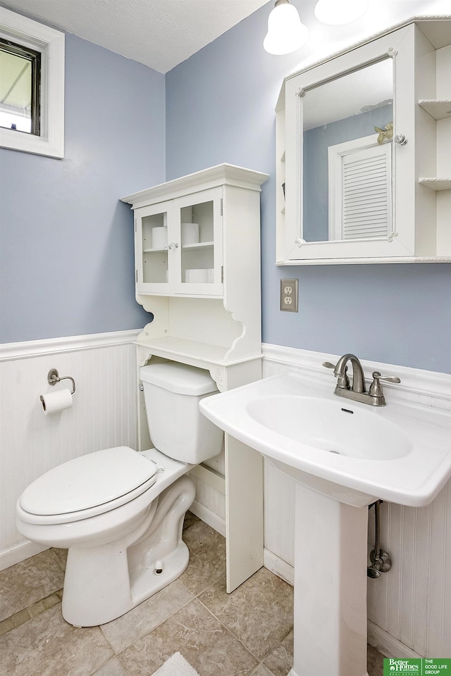 half bath featuring wainscoting and toilet