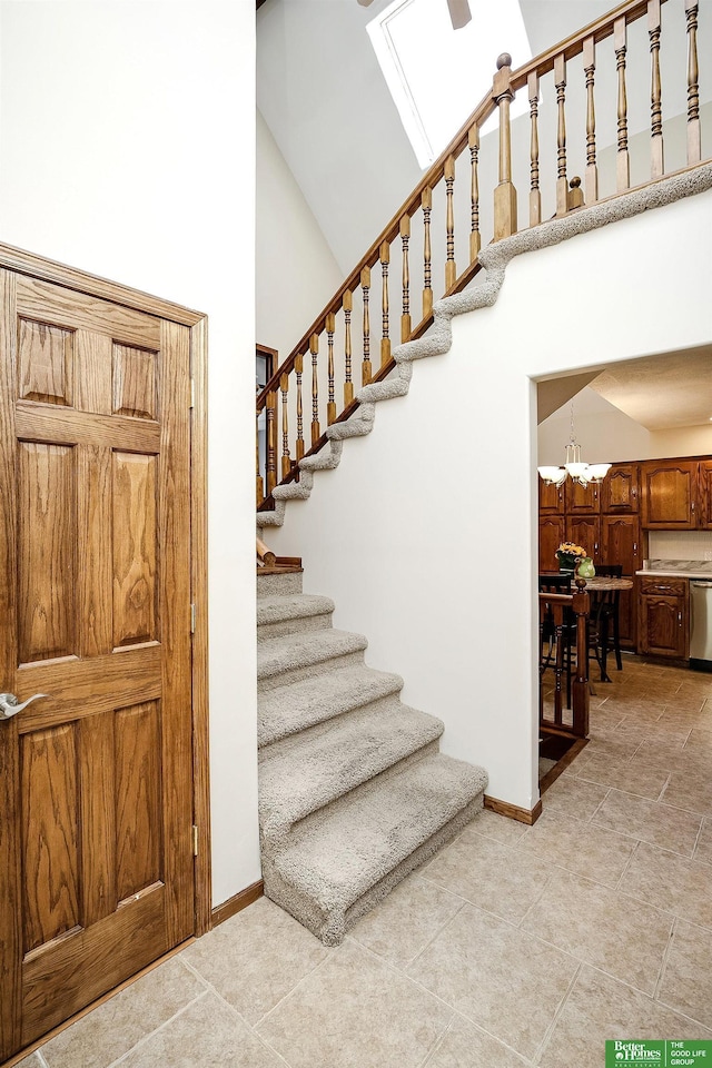 stairway with high vaulted ceiling, baseboards, and a chandelier