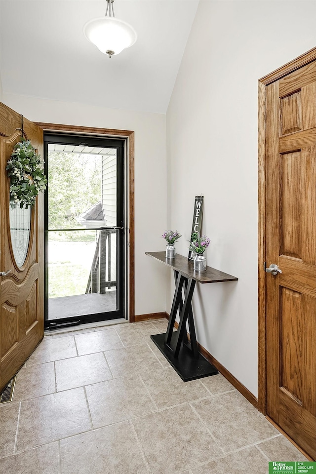 foyer featuring lofted ceiling and baseboards