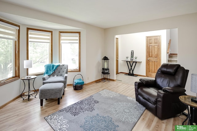 living area featuring wood finished floors, baseboards, and stairway