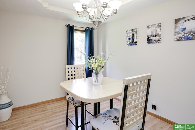 dining space featuring a chandelier, light wood finished floors, and baseboards