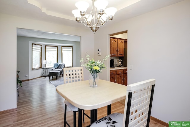 dining area with a chandelier, light wood-type flooring, and baseboards