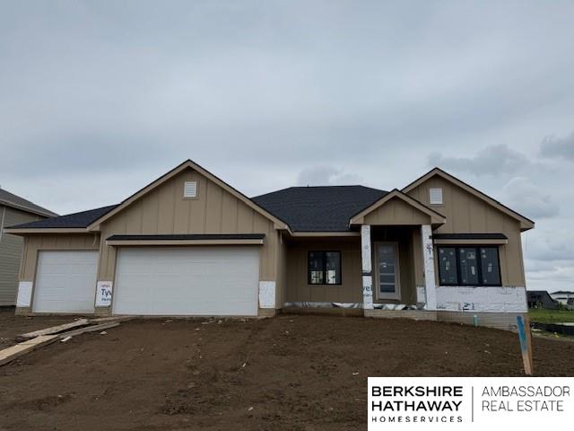 12378 Fenwick St, Papillion, NE 68046 - view of front of property with board and batten siding, an attached garage, and dirt driveway