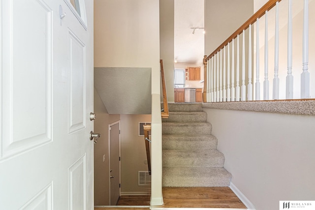 staircase featuring wood finished floors and baseboards