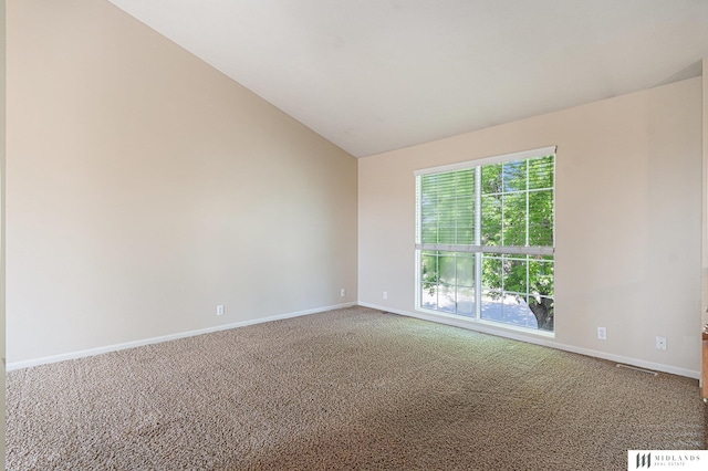 carpeted empty room with baseboards and vaulted ceiling